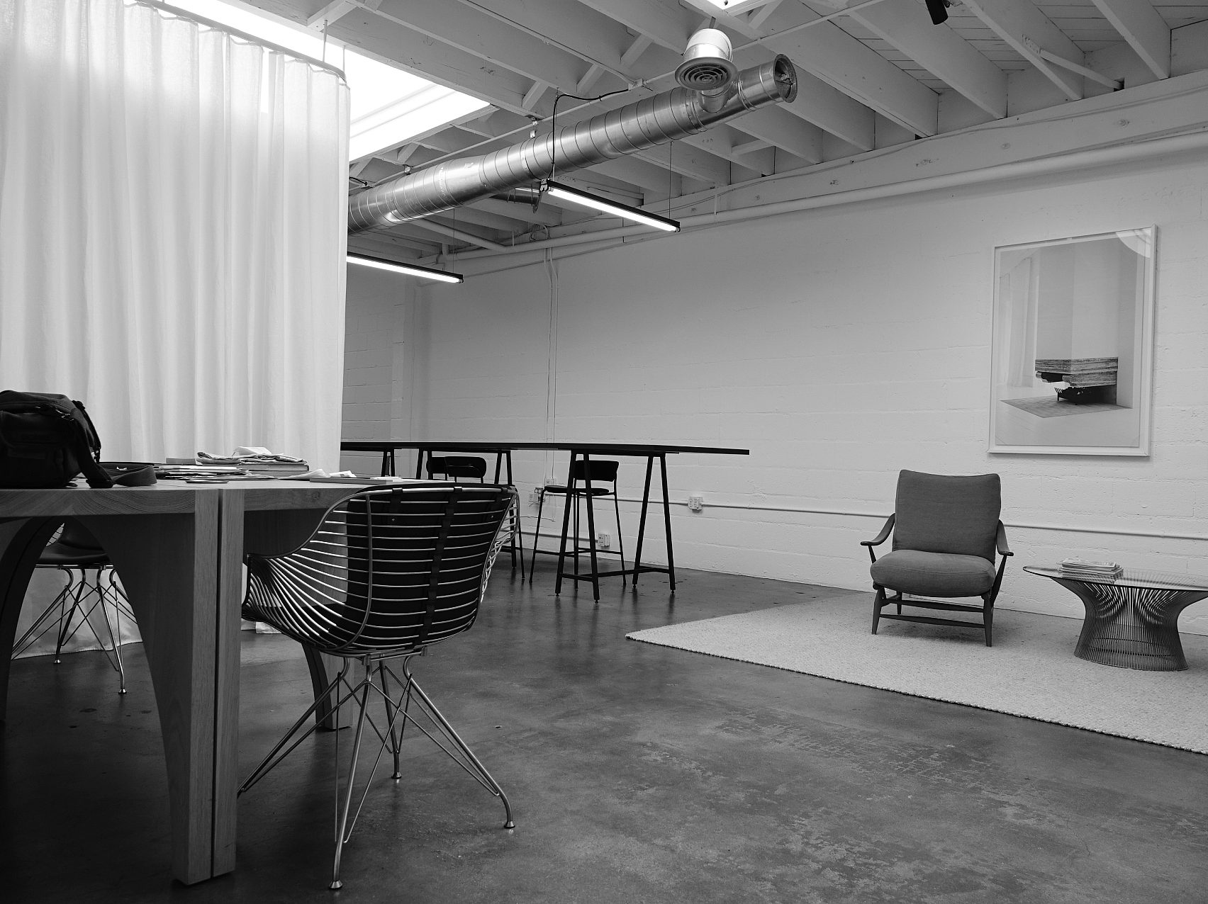 Black and white image of the studio, with multiple seating areas and artwork on th wall.