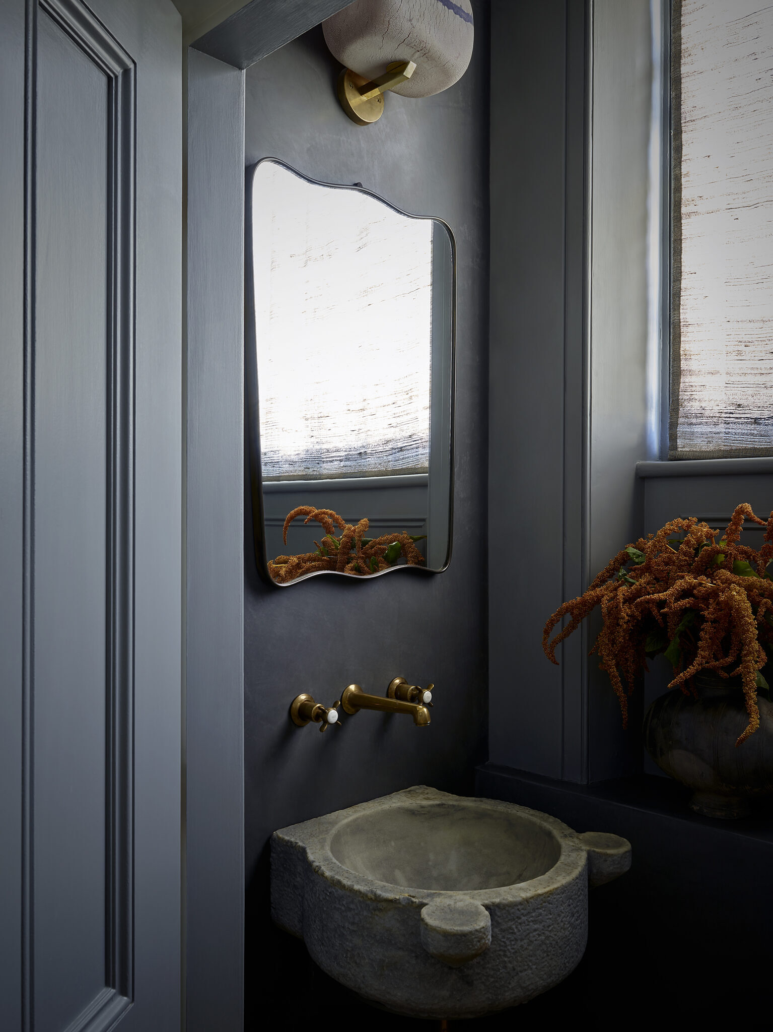 Kitchen close up of blue/gray walls, stone sink and gold hardware.