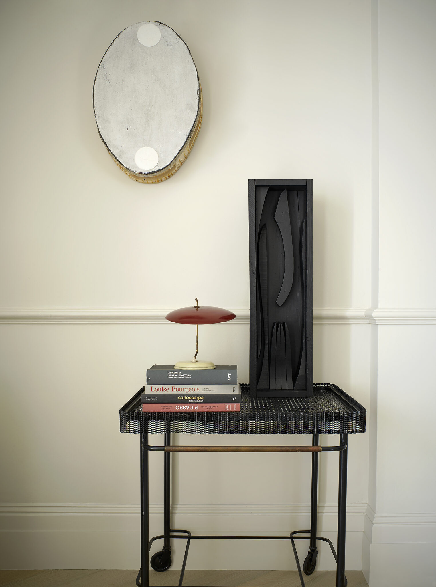 Image of a roller desk, which has a small lamp, books, and artwork on the top.