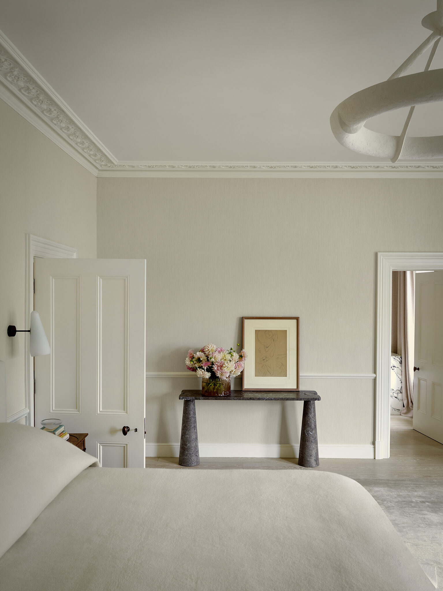 Image of a bedroom, with flowers and a piece of artwork sitting on top of a stone-like table.