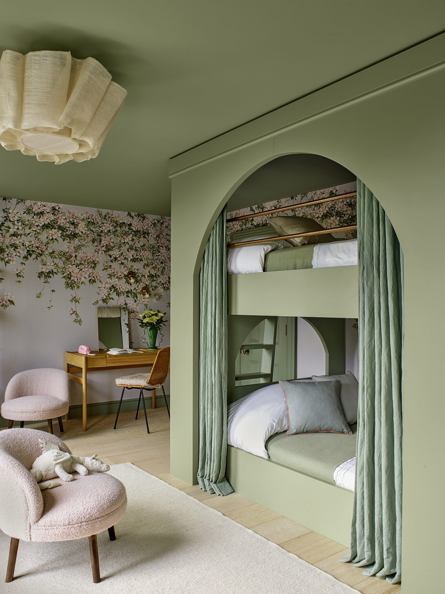 Children's bedroom, with a bunk bed with custom arc'ed sides. There are two chairs and a children's desk in the room and a light colored rug.