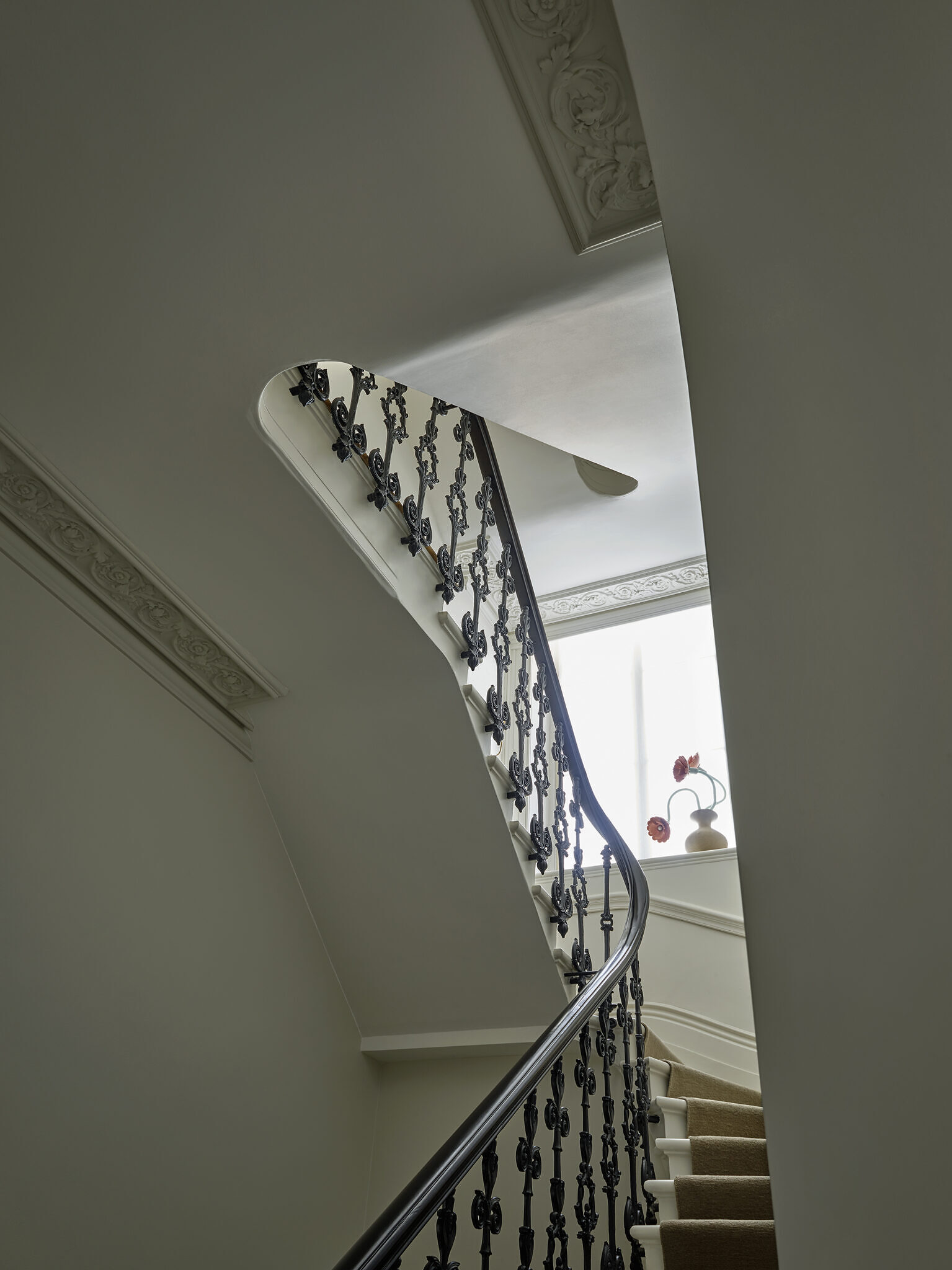 Image of the staircase, with black rails and white ceilings.