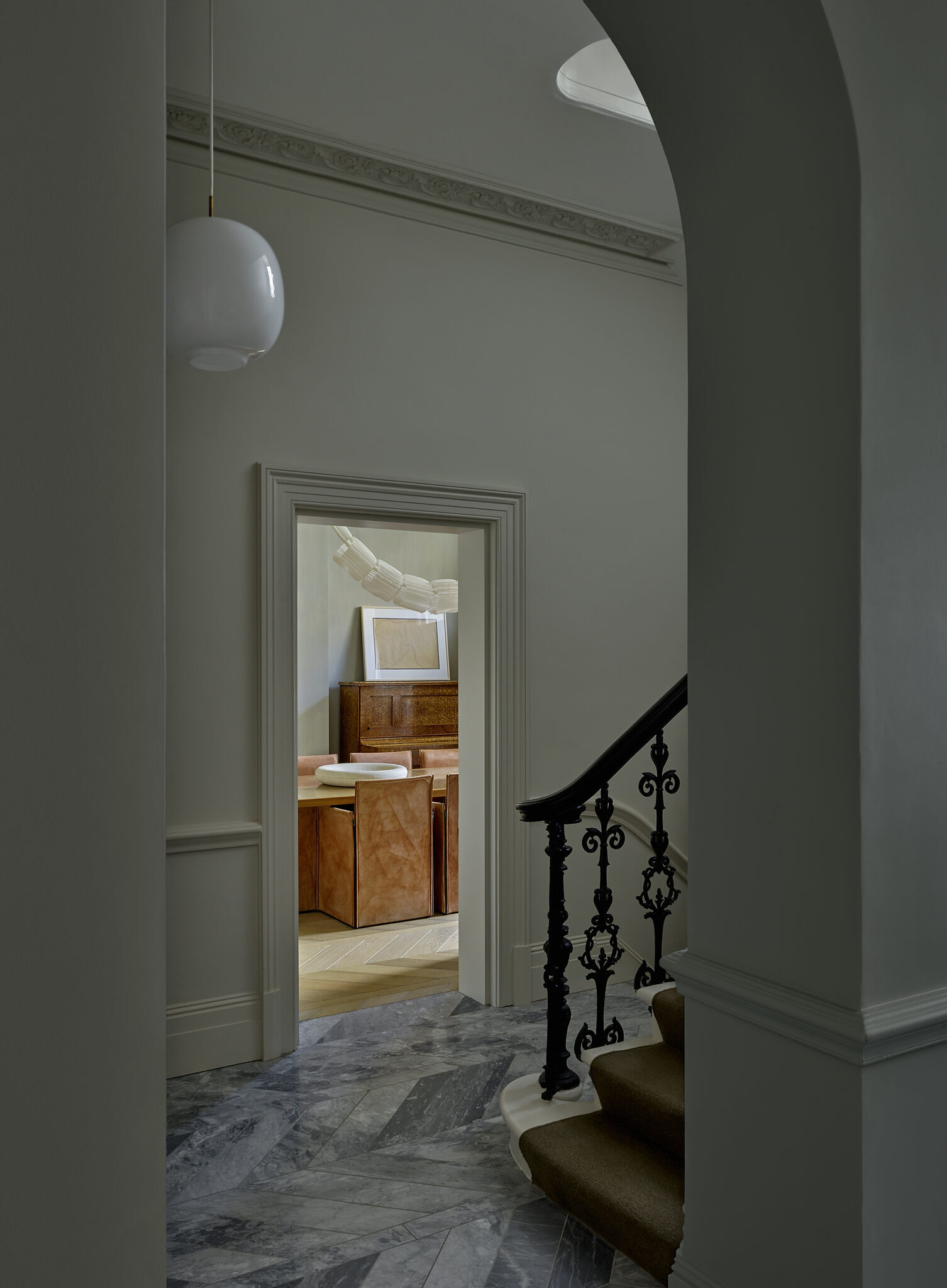 Hallway image showing the staircase, a white bulb lamp hanging above, and the dining room peeking through across the image.